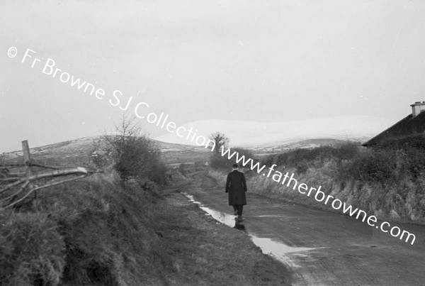 MAN WALKING ALONG ROAD